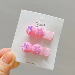 Detail of pink floral hair clips for girls with sequins and soft plush balls on card