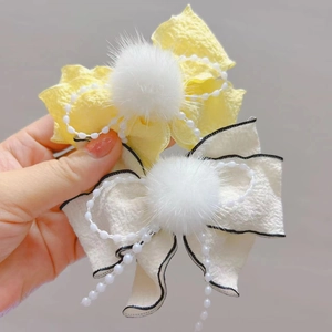 Dettaglio di fermagli per capelli a fiocco per bambine con pompon e catenelle di perle