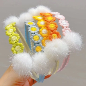 Detail of colorful knitted daisy headbands featuring soft faux fur mink balls for girls