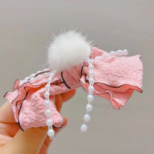 Dettaglio del fermaglio per capelli con fiocco rosa e pompon in finta pelliccia