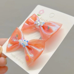 Détail macro de barrettes à cheveux orange pailleté avec fleurs en perles sur carte