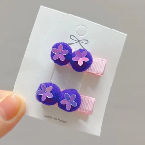 Detail of sequin flower hair clips with purple pom poms on pink ribbon-wrapped pins