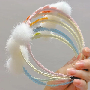 Close-up of wavy headbands with mink fur balls and colorful handmade knit flowers