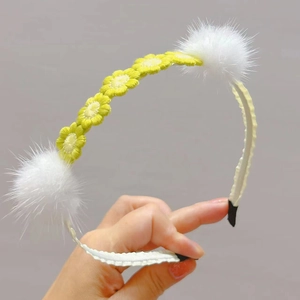 Close-up of handmade crochet headband with yellow daisy flowers and white mink fur balls