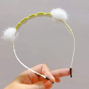 Detailed macro view of white faux fur pom poms and crochet floral accents on a cream headband