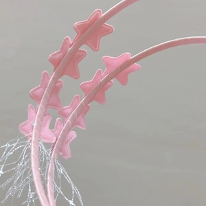 Détail d'un serre-tête rose avec étoiles à paillettes et glands brillants