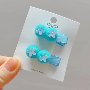 Detail of blue pompom hair clips with white sequin flowers for girls on a card