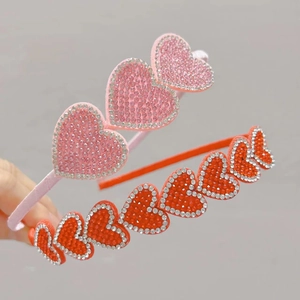 Close-up of sparkling rhinestone heart headbands in pink and orange for girls