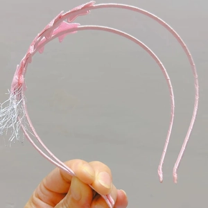 Détail du serre-tête en satin rose avec étoiles brillantes et franges argentées