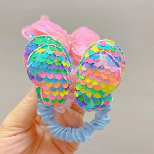 Detailed view of handmade rainbow sequin bow hair tie with blue telephone wire elastic band