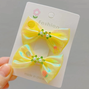 Détail de barrettes à cheveux jaunes avec nœuds, paillettes, perles et tulle