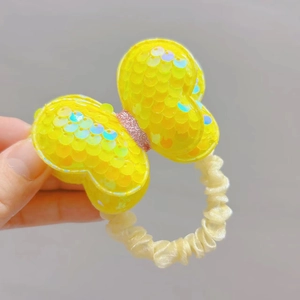 Detail of yellow sequin bow hair tie with ruffled tulle scrunchie for girls