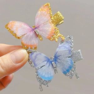 Close-up of glitter butterfly hair clips with gradient tulle wings in hand