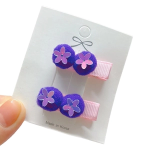 Set of two purple plush flower hair clips with sequins on a white display card