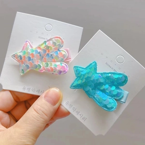 Detail of colorful sequin star hair clips with glitter finish and duckbill clips