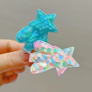 Close-up of glitter star hair clips with shimmering blue and pink sequins for girls