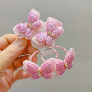 Detailansicht pinkfarbener Glitzer-Schmetterling-Haarklammern und Haargummis mit Strass