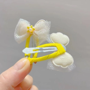Close-up of yellow lace bow and cloud hair clips with pearls and sequins for girls