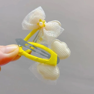 Detail of yellow flower hair clip with white glitter bow and faux pearl on ribbon-wrapped clip