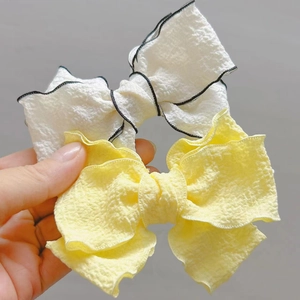 Close-up of three-layered seersucker bow hair clips in white and yellow colors