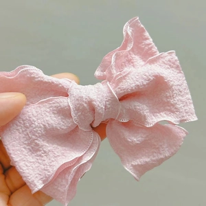 Detail of pink bow hair clip featuring textured seersucker fabric and layered design