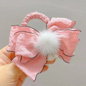 Dettaglio di fiocco rosa per capelli con pompon in ecopelliccia bianca e tessuto