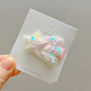 Detailed macro view of colorful sequin star hair clip on a white cardboard display