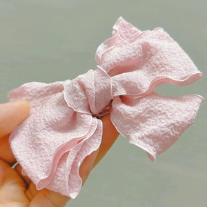 Detailed view of layered pink seersucker fabric on a large sweet style bow hair clip
