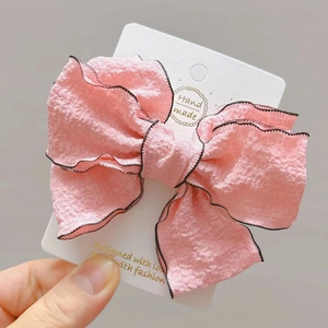 Detail of pink layered bow hair clip with black stitched edges on display card