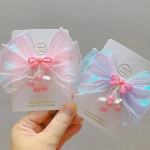 Close-up of organza bow hair clips with heavy beaded shell tassels on display card