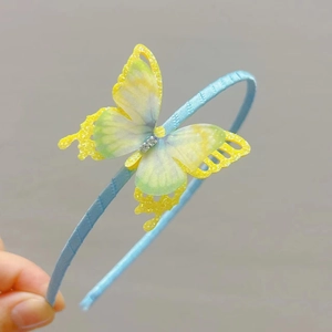Detail of light blue hairband with a yellow-green gradient sequined butterfly and rhinestones