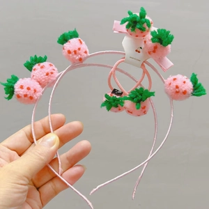 Detail von rosa gestrickten Erdbeer-Haarklammern und Haarbändern auf einer Karte