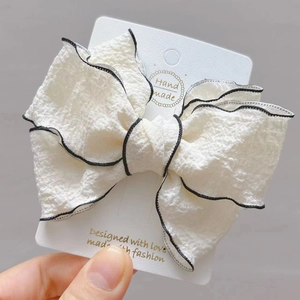 Elegant cream white oversized triple bow hair clip with black wavy edge on display card