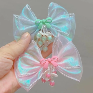 Close-up of iridescent mermaid bow hair clips with beaded tassels and shell accents