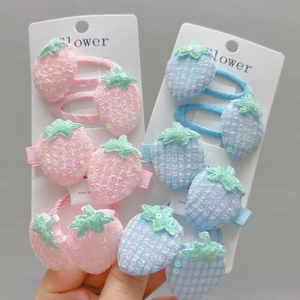 Detail view of pink and blue sequin strawberry hair clips and elastics on display card