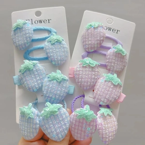 Detail of sequined strawberry hair clips and elastics in pastel blue and purple colors