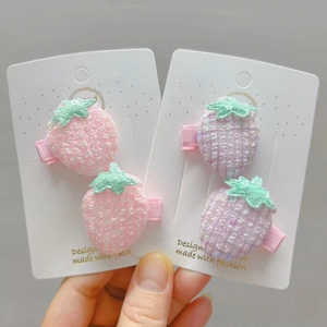 Détail de barrettes fraises à paillettes en broderie rose et violette sur carte blanche
