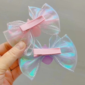 Détail de barrettes à nœud rose iridescent avec bord argenté et base en ruban doux