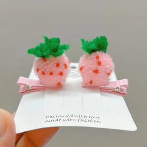 Nahaufnahme von rosa Häkel-Erdbeeren-Haarspangen mit grünen Blättern und orangefarbenen Punkten