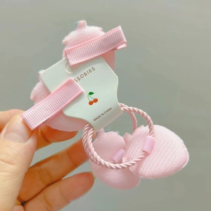 Vue détaillée de barrettes à ruban rose et d'élastiques à cheveux sur une carte support