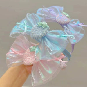 Détail de barrettes à nœuds en organza avec décor de fraises pailletées pour filles