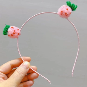 Detailaufnahme eines rosa Kinderhaarreifs mit niedlichen 3D-Plüsch-Erdbeer-Dekorationen