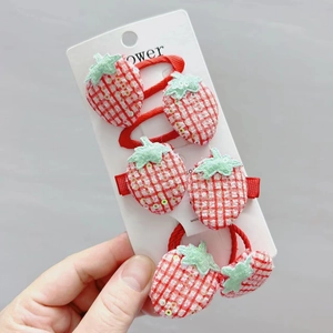 Detail of sequined strawberry hair clips and elastics on display card in hand