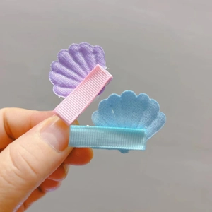 Détail de barrettes à cheveux en tissu en forme de coquillage avec broderie et rubans