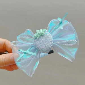 Détail d'un nœud à cheveux en organza bleu ciel avec une décoration de fraise pailletée