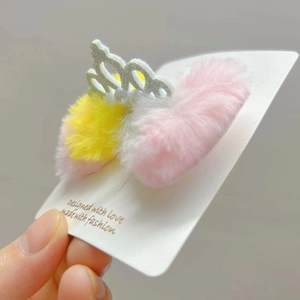 Dettaglio del fermaglio in peluche con corona d'argento e perle su pompon morbidi