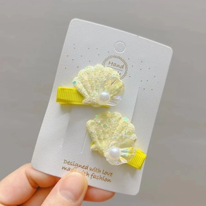 Détail de barrettes coquillages jaunes à paillettes avec perle et ruban gros-grain
