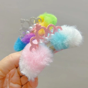 Dettaglio del fermaglio in peluche arcobaleno con corona glitterata e perle