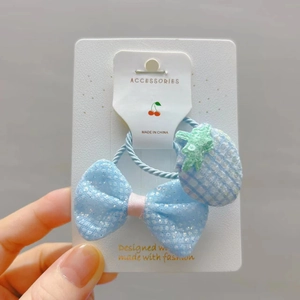 Détail d'un nœud bleu à paillettes et d'un élastique fraise sur une carte