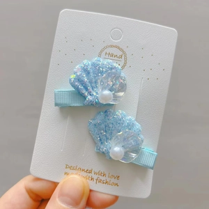 Détail de pinces à cheveux coquillage bleu clair pailleté avec perles blanches